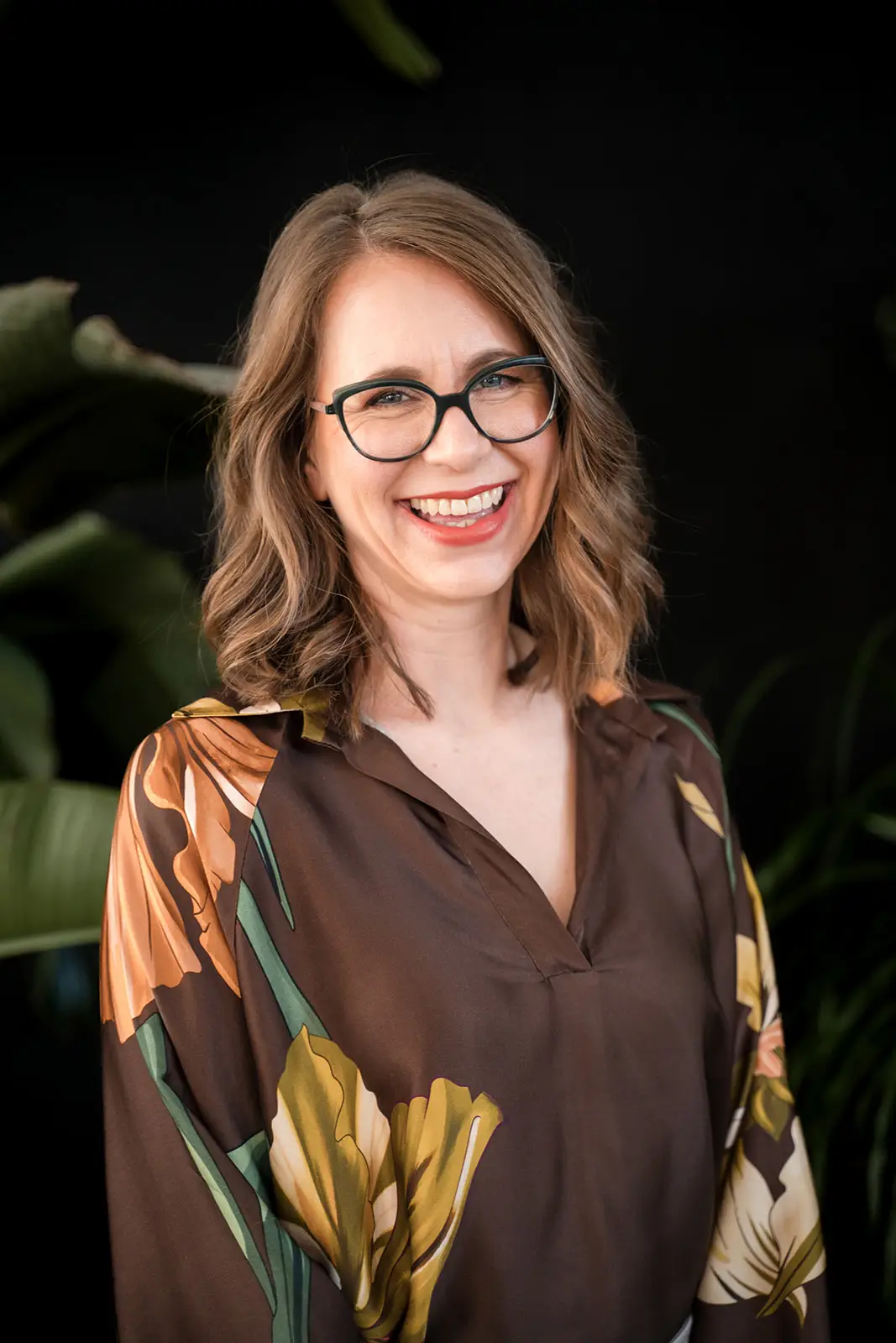 Yvonne Uehlein (Ärztin für TCM im Allgäu) lächelt in die Kamera vor dunklem Hintergrund